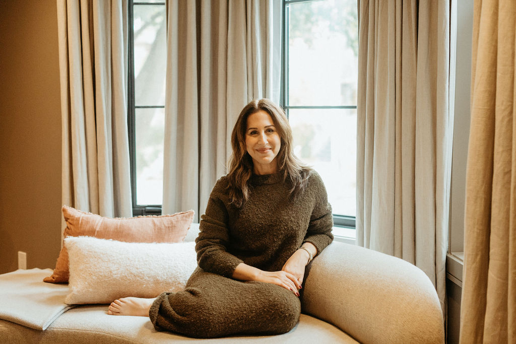 Bonnie Altro seated on a couch in front of large windows